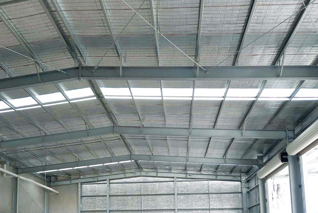 Metal roofing contractor showcasing the installation of heat reduction and reflective insulation for industrial, warehouse, or factory roofs.